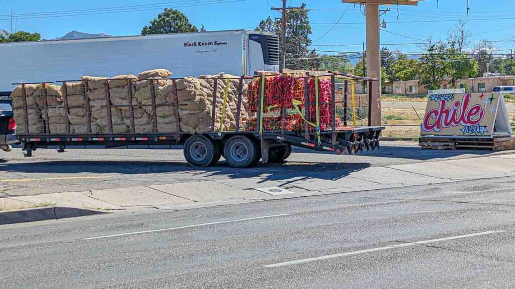 A chile truck loaded with sacks of Hatch green chile and lots of chile ristras pulling into a chile store in Albuquerque